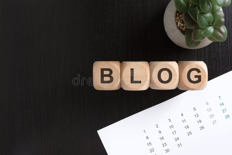 Träklossar med ordet BLOGG bredvid en kalender och en växt